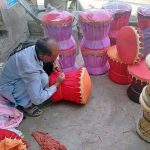 A laborer takes shelter in the shade near Shahdara Road while crafting a bamboo stools, aiming to sell them in the local market
