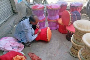 A laborer takes shelter in the shade near Shahdara Road while crafting a bamboo stools, aiming to sell them in the local market