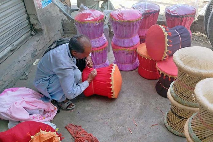 A laborer takes shelter in the shade near Shahdara Road while crafting a bamboo stools, aiming to sell them in the local market