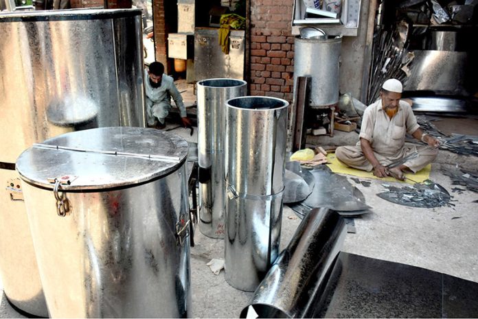 Workers busy in preparing huge iron containers for the storage of wheat to the customers at their workplace