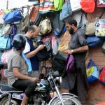 People buying bags from a vendor's roadside stall in the city
