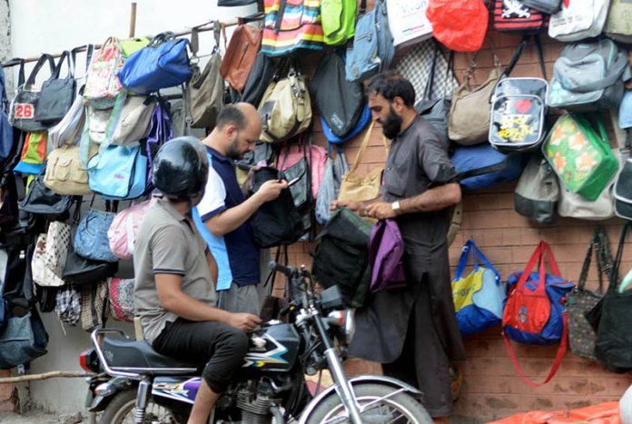 People buying bags from a vendor's roadside stall in the city