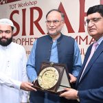 Program host Qamarul Haq presents a shield to Federal Minister for Planning, Development and Special Initiatives, Ahsan Iqbal, during the Seerah Workshop at Seerah Center