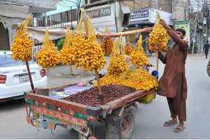 A street vendor arranging freshly harvested dates on his handcart to attract customers at local market.