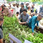 Gardening enthusiasts browse and purchase low-cost plants from a roadside vendor stall in Latifabad