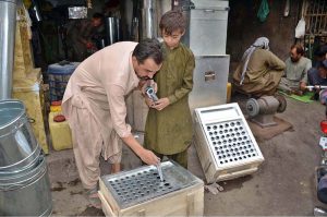 A young boy learns to prepare traditional ice cream (Kulfi) boxes under the guidance of his master amid rising summer demand