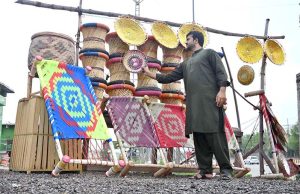 A vendor arranges beautiful handicrafts items made from cane and palm leaves at a roadside near the toll plaza at 17 Meel in the federal capital