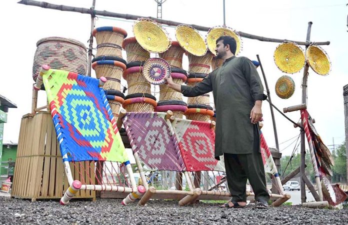 A vendor arranges beautiful handicrafts items made from cane and palm leaves at a roadside near the toll plaza at 17 Meel in the federal capital