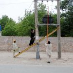 MEPCO staff work on repairing an electricity fault on a tower along the roadside in the city.