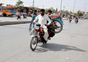A motorcyclist transports a out of order motorcycle to a nearby mechanic for repair on Joint Road in Quetta