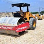 Labourers use heavy rollers to level and prepare the newly constructed road for carpeting during a city development project at Auto Bahn Road