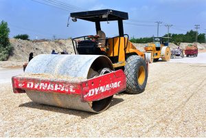 Labourers use heavy rollers to level and prepare the newly constructed road for carpeting during a city development project at Auto Bahn Road