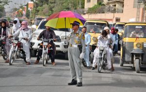 A traffic police officer shields himself with an umbrella while on duty at Inscumb Road,Quetta braving the intense summer heat to ensure smooth traffic flow.