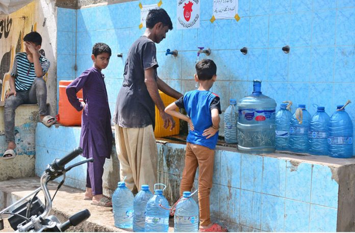 Youngsters fill their bottles with clean drinking water from a filtration plant in Phuleli area to stay hydrated amid the sweltering summer heat