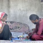 A gypsy couple enjoys a game of Ludo on a roadside footpath, turning leisure time into a simple moment of joy