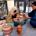 A woman displaying and selling clay pots to attract the customers at Namak Mandi Chowk.