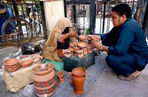 A woman displaying and selling clay pots to attract the customers at Namak Mandi Chowk.