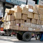 A daily-wage laborer pulls an overloaded cart of goods for transport and delivery to the market in Raja Bazaar, one of the busiest areas in the twin cities