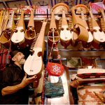 An elderly vendor displays traditional musical instruments, including the Rabab, to attract customers at his roadside shop near Dabgari area.