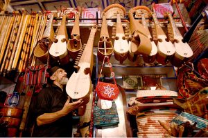 An elderly vendor displays traditional musical instruments, including the Rabab, to attract customers at his roadside shop near Dabgari area.