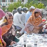 Women browse sunglasses for purchase at a street stall in the Saddar area