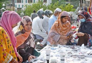 Women browse sunglasses for purchase at a street stall in the Saddar area