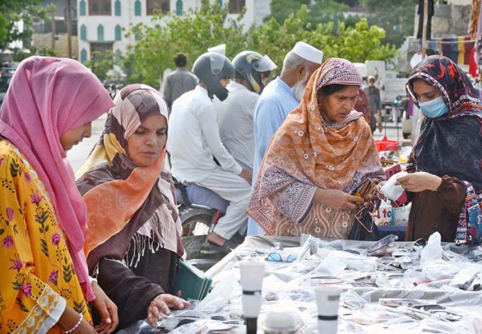 Women browse sunglasses for purchase at a street stall in the Saddar area