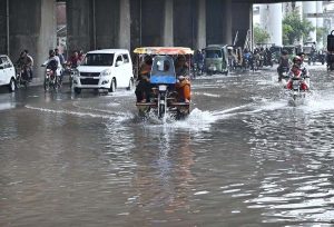 Vehicles passing through accumulated water on Multan Road after rain in the provincial capital