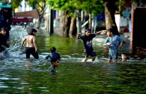 Children enjoy a playful bath in stagnant rainwater collected on a street after recent showers.