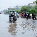 A view of a rain-inundated road as a tricycle rickshaw struggles to pass through a flooded street during a heavy monsoon downpour in the city