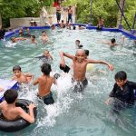 Youngsters cool off in a village swimming pool to escape the sweltering summer heat in Ghulam Bhutto