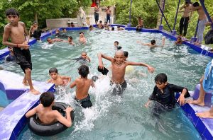 Youngsters cool off in a village swimming pool to escape the sweltering summer heat in Ghulam Bhutto