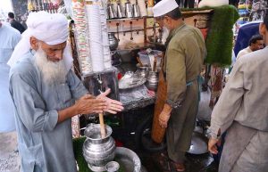 An aged man preparing traditional drink Lassi to attract the customers at Shoba Bazar.