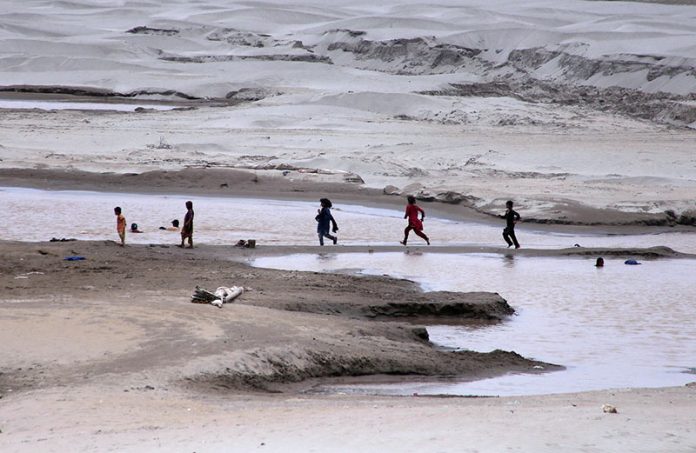 Children play without fearing the threat of floods on the banks of the Indus River near Jamshoro