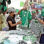 A vendor displays Independence Day-themed girls’ shirts, national flags, and badges at Paper Market as preparations for Independence Day celebrations gain momentum