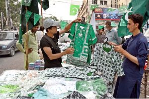 A vendor displays Independence Day-themed girls’ shirts, national flags, and badges at Paper Market as preparations for Independence Day celebrations gain momentum
