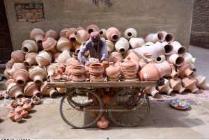 An elderly man displays clay pots on his hand cart to attract customers at Kumhar Para, showcasing traditional craftsmanship