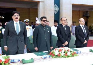 Governor Kamran Khan Tessori, Chief Minister Murad Ali Shah, and Justice Junaid Ghaffar stand for the national anthem during the oath-taking ceremony at Governor House