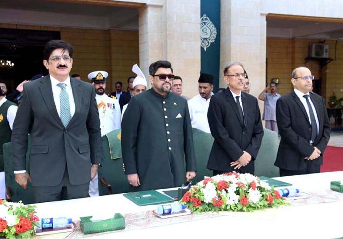 Governor Kamran Khan Tessori, Chief Minister Murad Ali Shah, and Justice Junaid Ghaffar stand for the national anthem during the oath-taking ceremony at Governor House