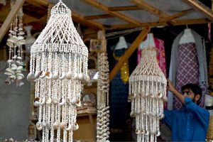 A shopkeeper arranges beautiful seashell decorations and chandelier at his shop to attract tourists at Lok Virsa in the federal capital