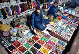 A street vendor arranges colorful gemstones and beautiful rings to attract customers at his roadside setup in a local market
