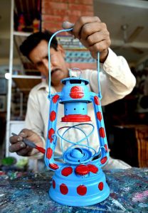A shopkeeper arranges beautiful seashell decorations and chandelier at his shop to attract tourists at Lok Virsa in the federal capital