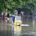 An auto rickshaw passing through accumulated water on the road after rain in the Provincial Capital.