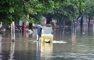 An auto rickshaw passing through accumulated water on the road after rain in the Provincial Capital.