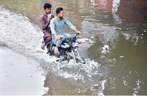 An auto rickshaw passing through accumulated water on the road after rain in the Provincial Capital.