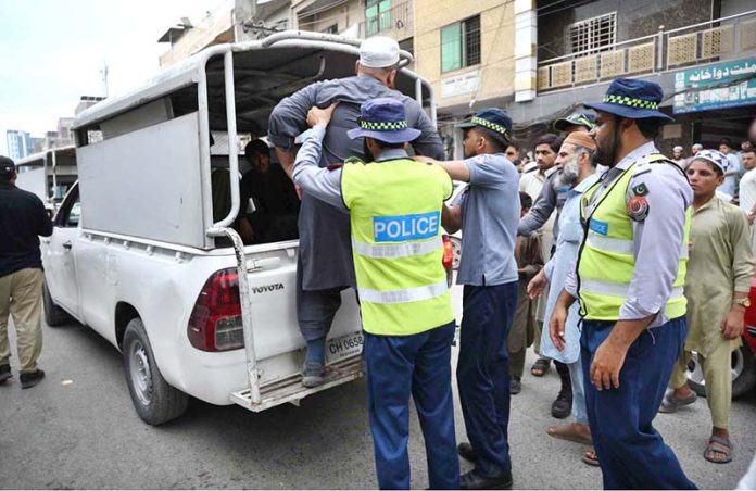 Traffic police officials arrest a man during an anti-encroachment operation in the Namak Mandi area