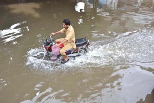 An auto rickshaw passing through accumulated water on the road after rain in the Provincial Capital.