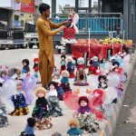 A roadside vendor lines up a row of colorful dolls along GT Road,to attract passersby and earn a livelihood for his family