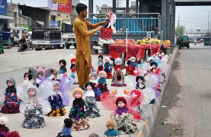 A roadside vendor lines up a row of colorful dolls along GT Road,to attract passersby and earn a livelihood for his family