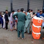 People queue for their turn to receive free food as volunteers distribute free food among people in Kotli Bahram